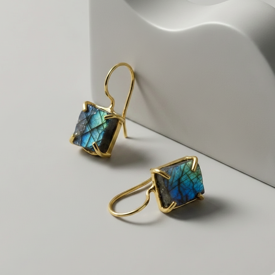 Gold plated hook earrings with raw Labradorite stones on a light grey background