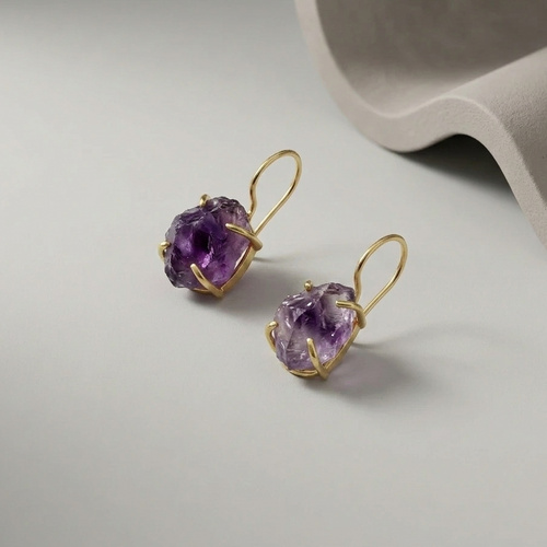 Gold plated hook earrings with raw amethyst gemstones on a light grey background
