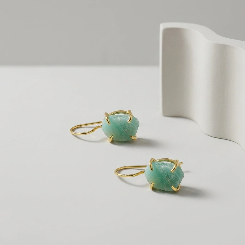 Pair of earrings with raw Amazonite gemstones a on a light grey background